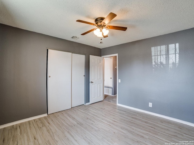 unfurnished bedroom with a textured ceiling, a closet, ceiling fan, and light hardwood / wood-style floors