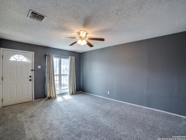 foyer featuring ceiling fan, carpet floors, and a textured ceiling