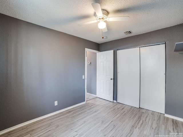 unfurnished bedroom featuring a textured ceiling, a closet, ceiling fan, and light hardwood / wood-style flooring