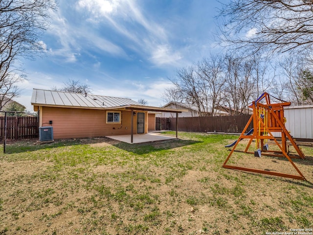 rear view of property featuring a playground, a yard, central air condition unit, and a patio area