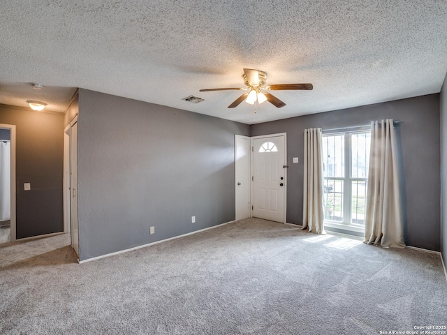 interior space featuring ceiling fan, light carpet, and a textured ceiling