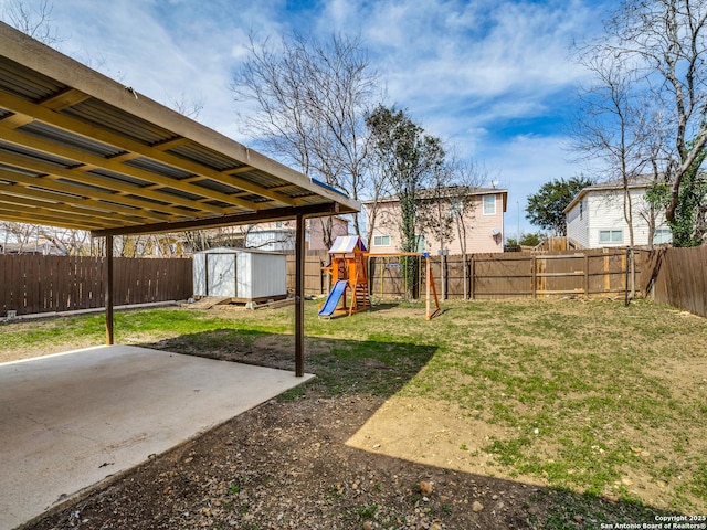 view of yard featuring a playground, a patio area, and a storage shed