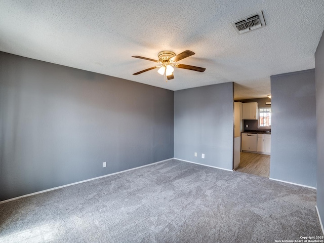 carpeted spare room with ceiling fan and a textured ceiling