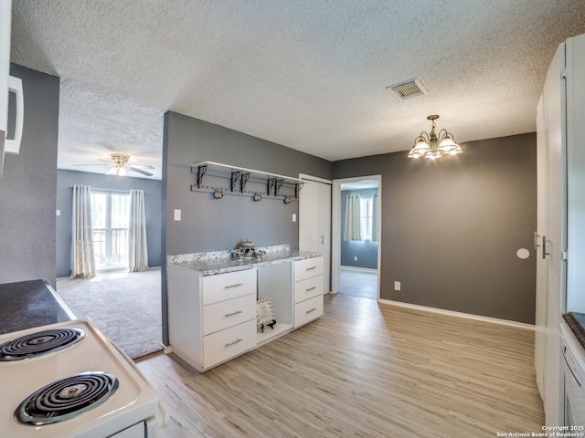 kitchen with white range with electric cooktop, pendant lighting, ceiling fan with notable chandelier, light wood-type flooring, and white cabinetry