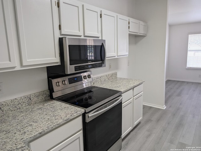 kitchen with white cabinetry, appliances with stainless steel finishes, light stone countertops, and light hardwood / wood-style floors