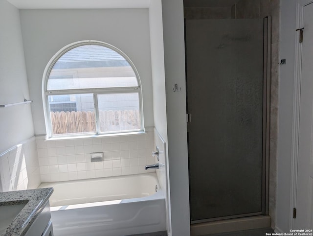 bathroom featuring vanity, independent shower and bath, and a wealth of natural light