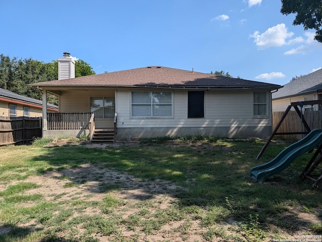 back of house featuring a yard and a playground