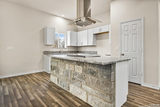 kitchen with light stone counters, white cabinetry, baseboards, dark wood-style floors, and island exhaust hood