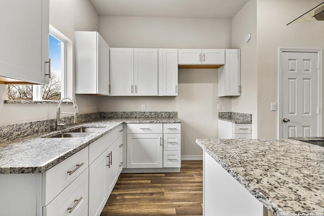 kitchen featuring white cabinetry, light stone counters, and a sink