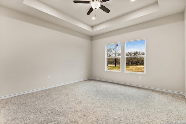 spare room with carpet floors, recessed lighting, a raised ceiling, a ceiling fan, and baseboards