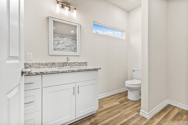 bathroom with baseboards, vanity, toilet, and wood finished floors