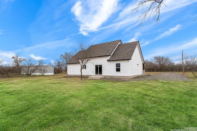 rear view of property with a lawn and roof with shingles