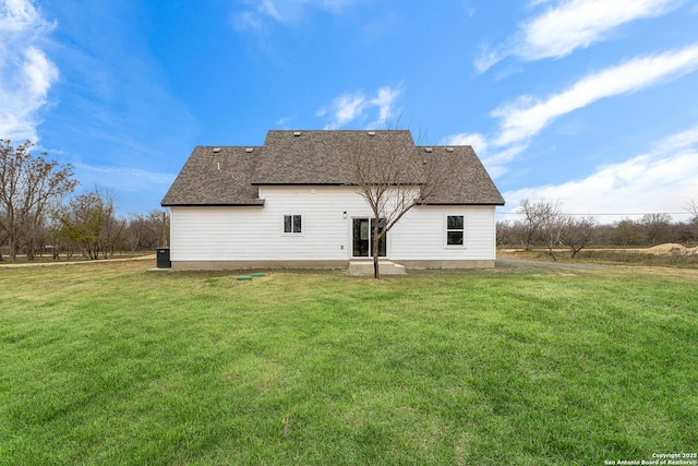 back of property featuring a shingled roof and a yard