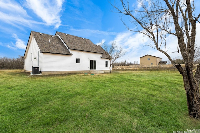 back of house featuring roof with shingles, central AC, and a yard