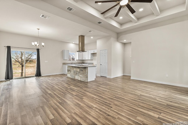 unfurnished living room featuring ceiling fan with notable chandelier, wood finished floors, visible vents, and baseboards