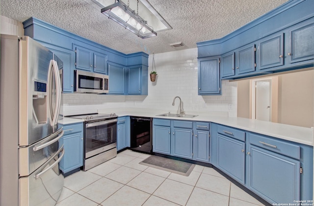 kitchen featuring stainless steel appliances, blue cabinets, backsplash, light tile patterned floors, and sink