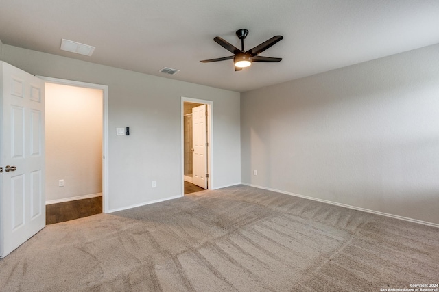 unfurnished bedroom featuring baseboards, carpet flooring, visible vents, ensuite bath, and a ceiling fan