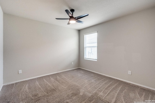 empty room featuring carpet, baseboards, and a ceiling fan