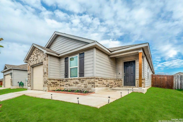 view of front of house with a front lawn, brick siding, an attached garage, and fence