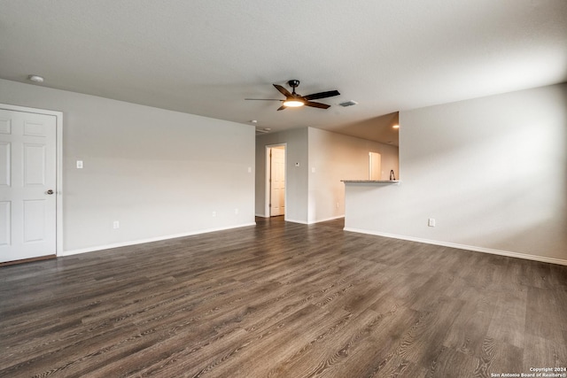 unfurnished living room featuring ceiling fan, visible vents, baseboards, and dark wood-type flooring