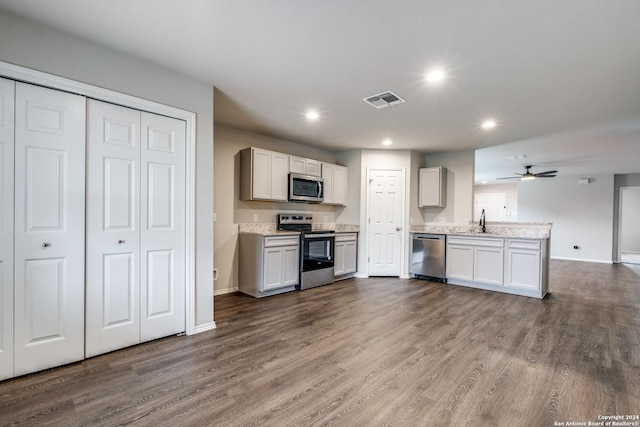 kitchen featuring dark wood finished floors, a peninsula, visible vents, appliances with stainless steel finishes, and a sink