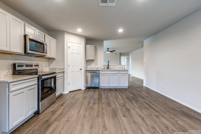 kitchen featuring visible vents, white cabinets, stainless steel appliances, light wood-style flooring, and a sink