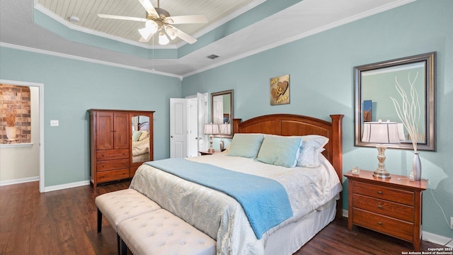 bedroom featuring dark wood-style flooring, visible vents, baseboards, and a tray ceiling