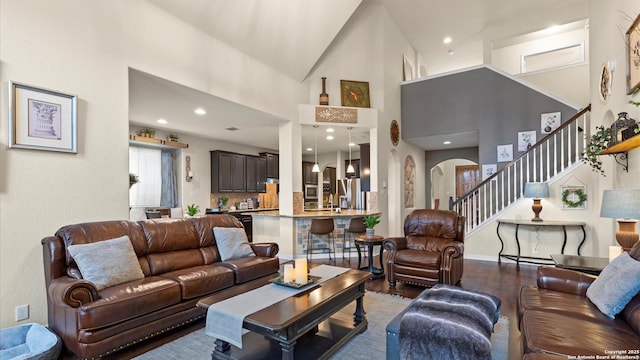 living area with stairway, high vaulted ceiling, recessed lighting, arched walkways, and wood finished floors