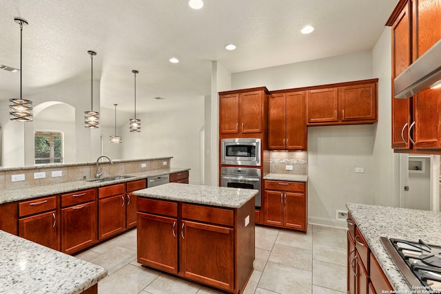 kitchen with a kitchen island, decorative light fixtures, appliances with stainless steel finishes, a sink, and light stone counters