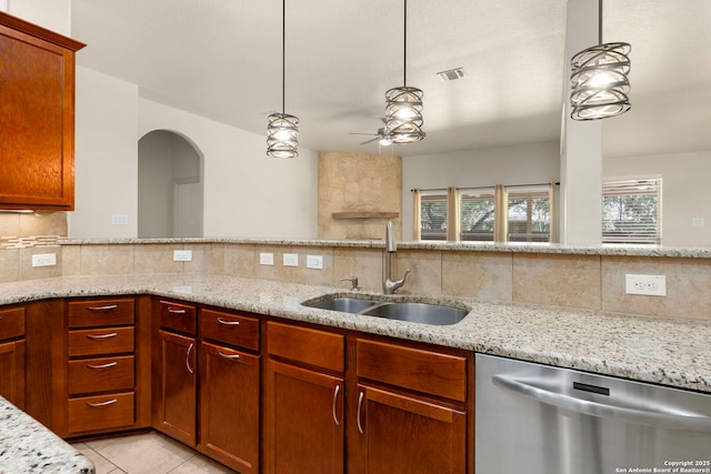 kitchen featuring pendant lighting, dishwasher, light stone counters, and a sink