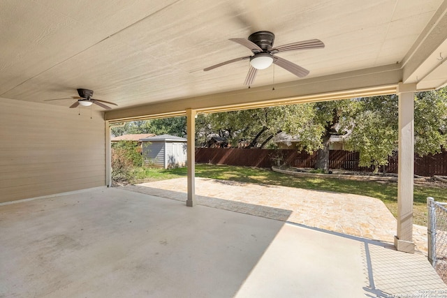 view of patio with a storage unit, a fenced backyard, an outdoor structure, and ceiling fan