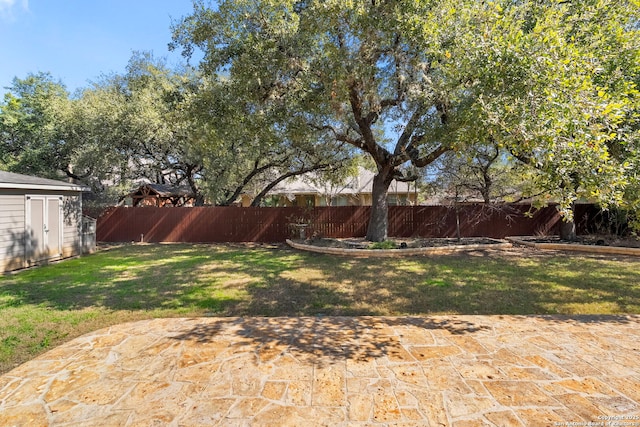 view of yard featuring a patio area, a storage unit, an outbuilding, and a fenced backyard