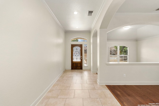 entrance foyer with visible vents, a wealth of natural light, and ornamental molding