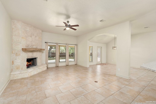 unfurnished living room with a fireplace, ceiling fan, arched walkways, light tile patterned flooring, and visible vents