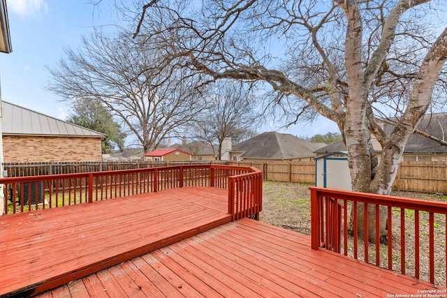 deck featuring a storage shed, an outbuilding, and a fenced backyard