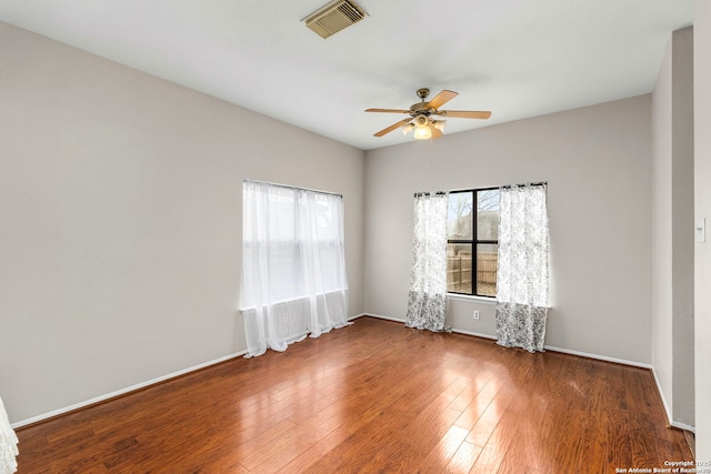 empty room with dark wood finished floors, visible vents, and a healthy amount of sunlight