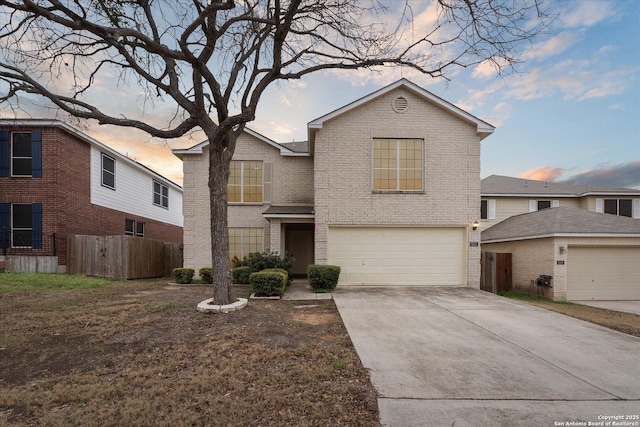 traditional-style home with fence, brick siding, concrete driveway, and a garage