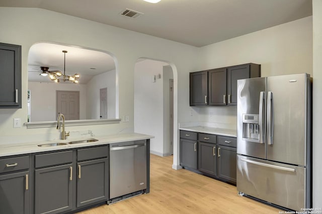 kitchen with a sink, visible vents, stainless steel appliances, arched walkways, and light stone countertops