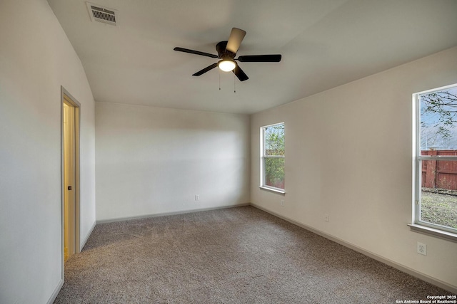 carpeted empty room with baseboards, ceiling fan, and visible vents