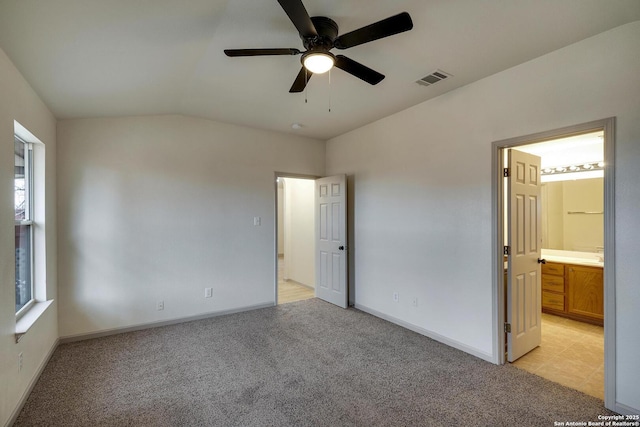 unfurnished bedroom with vaulted ceiling, visible vents, light colored carpet, and baseboards