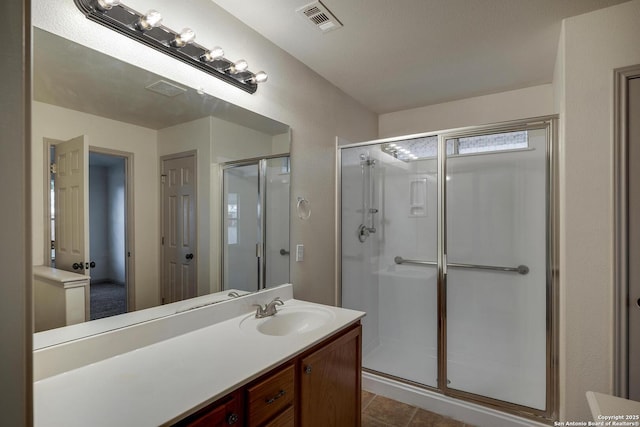 bathroom with a shower stall, visible vents, vanity, and tile patterned flooring