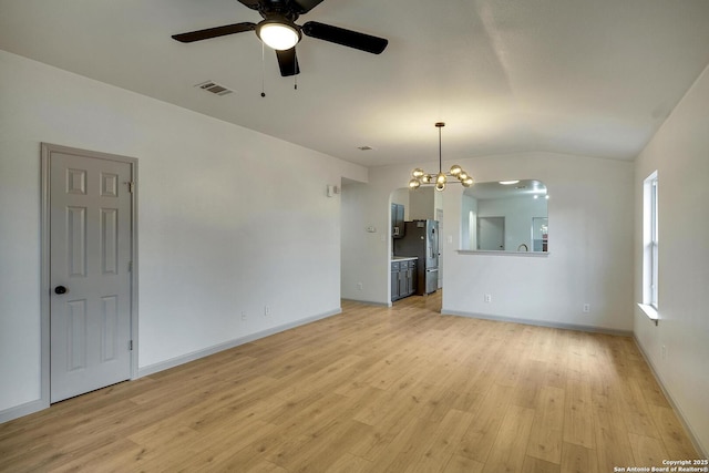 unfurnished living room with visible vents, lofted ceiling, ceiling fan with notable chandelier, and light wood finished floors