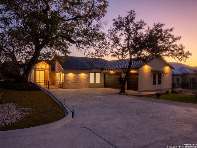 view of front of property with a standing seam roof, a garage, metal roof, stone siding, and concrete driveway