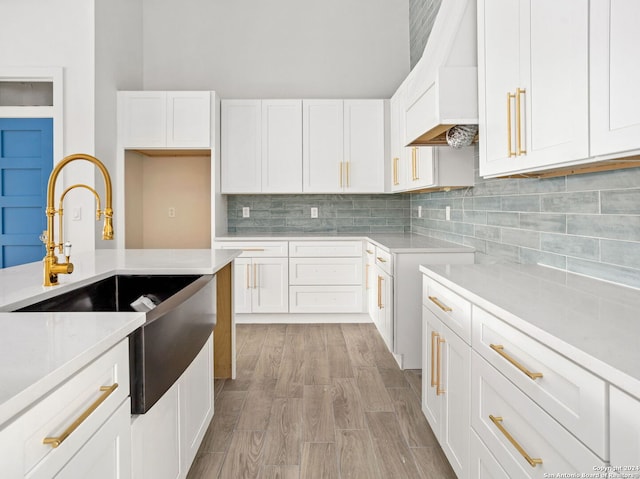 kitchen featuring a sink, backsplash, and white cabinetry