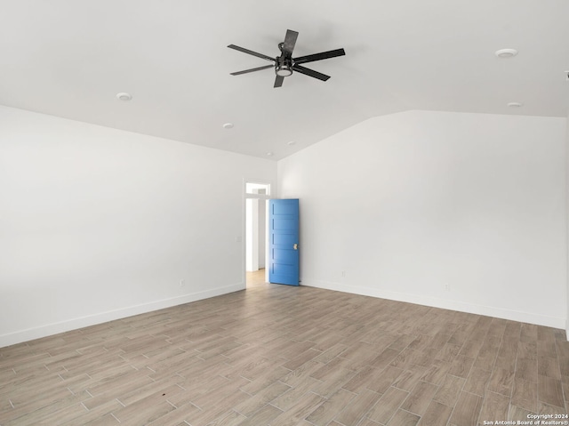 empty room featuring baseboards, lofted ceiling, and light wood finished floors