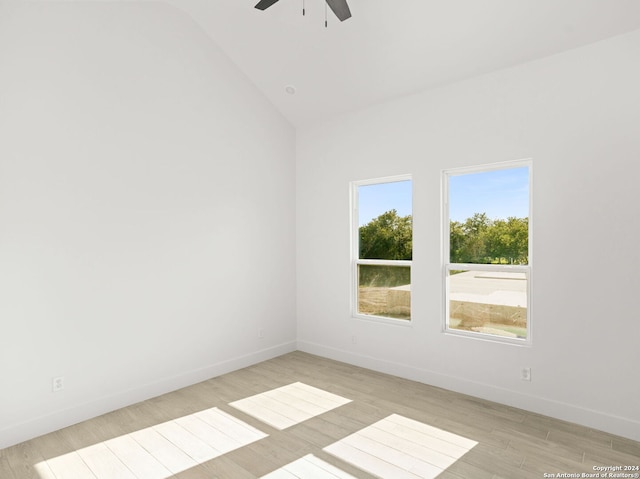 unfurnished room with ceiling fan, light wood finished floors, baseboards, and vaulted ceiling