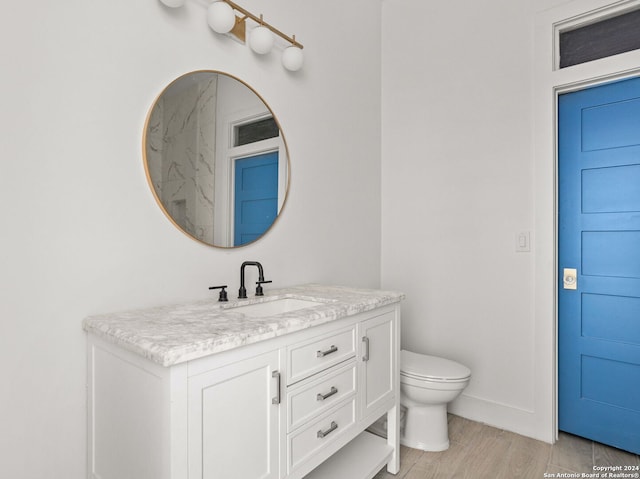 bathroom with wood finished floors, baseboards, vanity, and toilet