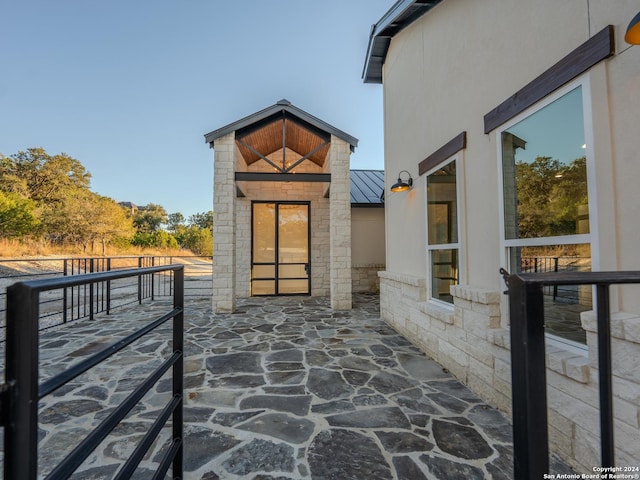 view of exterior entry featuring metal roof, stone siding, a patio area, a fireplace, and a standing seam roof