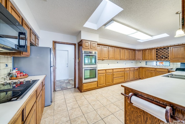 kitchen with a skylight, decorative light fixtures, light countertops, and black appliances