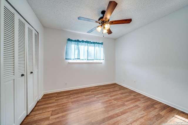 unfurnished bedroom with a textured ceiling, a closet, light wood-style floors, and baseboards